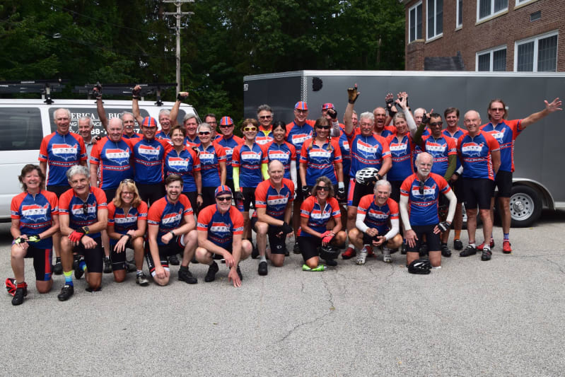 All the riders on day 50 pose in front of a school.